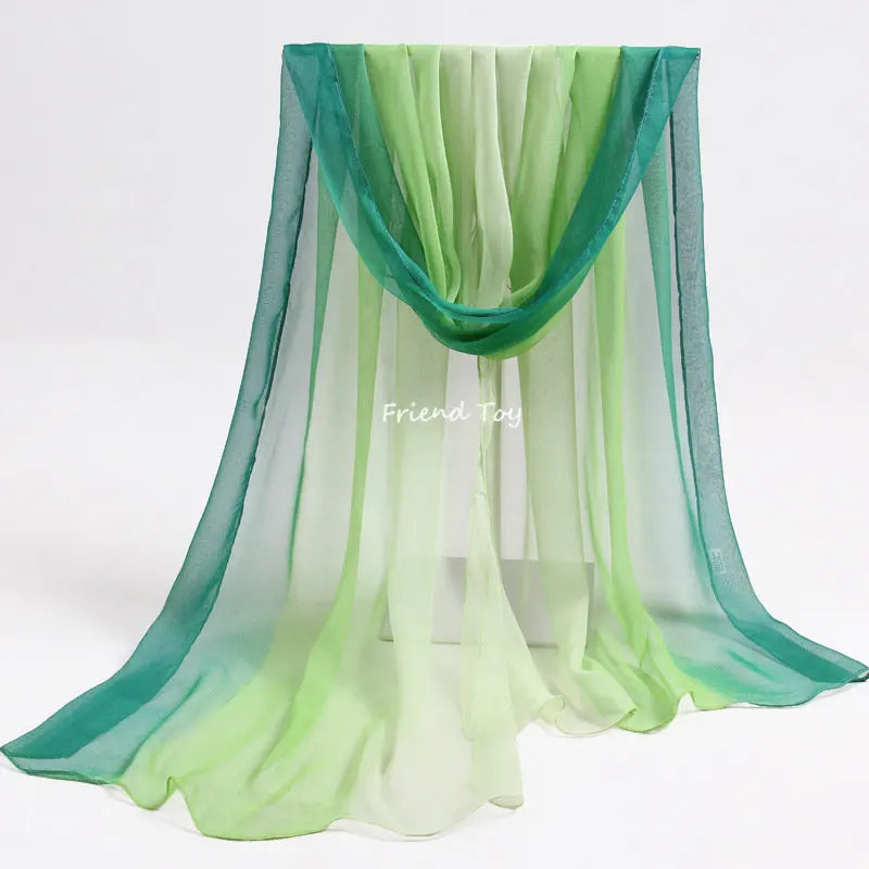 A set of sheer, flowing green and teal fabric scarves displayed hanging vertically.