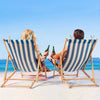 Two people relax in deck chairs on a beach with plastic clothespins visible.