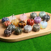 A collection of handcrafted natural stone pumpkin figurines in various colors and textures arranged on a wooden board.