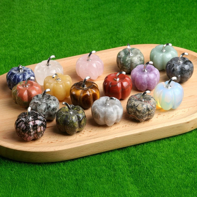 A collection of handcrafted natural stone pumpkin figurines in various colors and textures arranged on a wooden board.