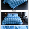 A light blue quilted duvet blanket with a diamond pattern displayed on a bed.
