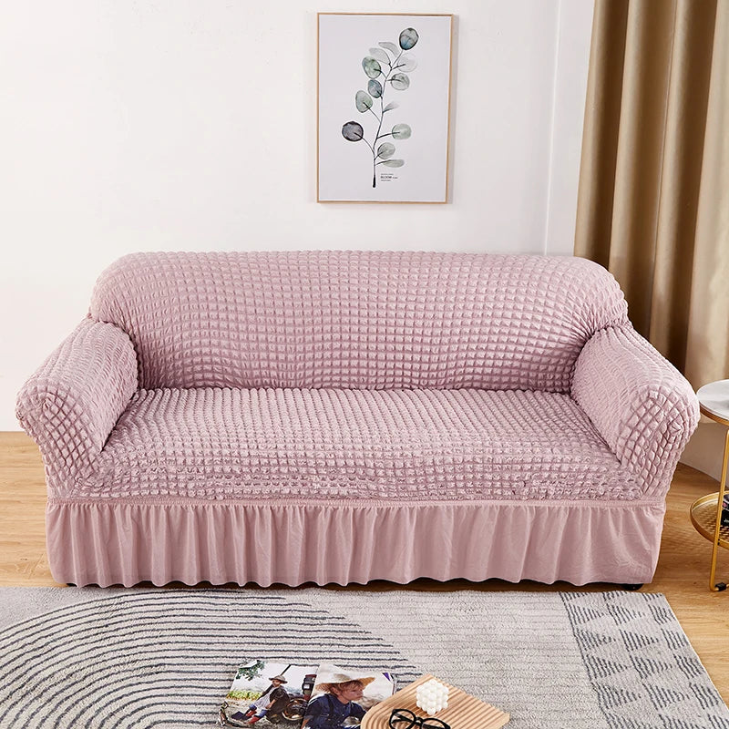 A light pink stretch knit sofa cover with a bubble lattice texture displayed on a wooden floor.