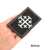 Black fabric patch embroidered with a white military cross design held in a hand.