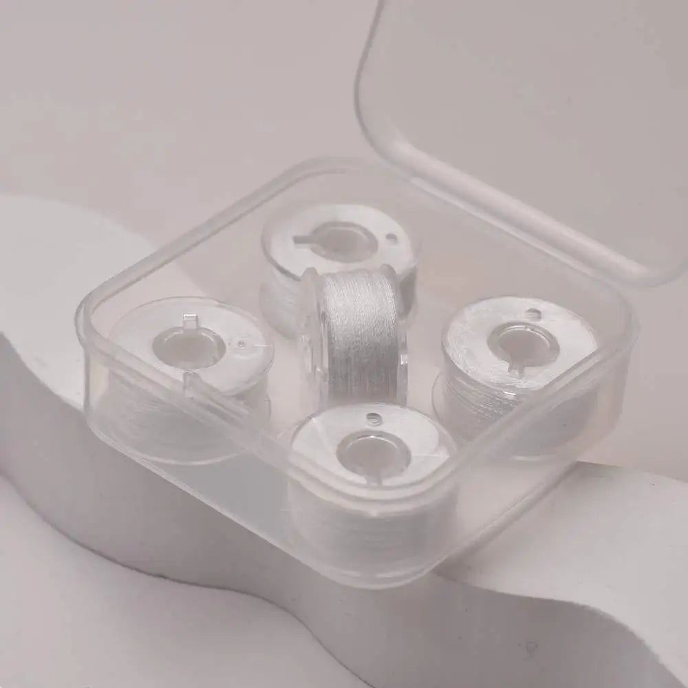 A clear plastic container holds four spools of prewound sewing machine bobbin threads.