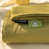 A stack of olive green organic cotton bedding, including a flat sheet and pillowcases, with a tag visible.
