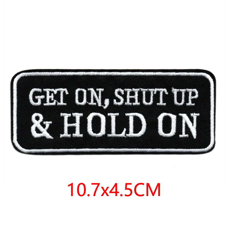 Black iron-on embroidered letter patch with white text that reads GET ON, SHUT UP & HOLD ON