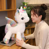 A young woman is interacting with a white unicorn plush toy in a modern indoor setting.