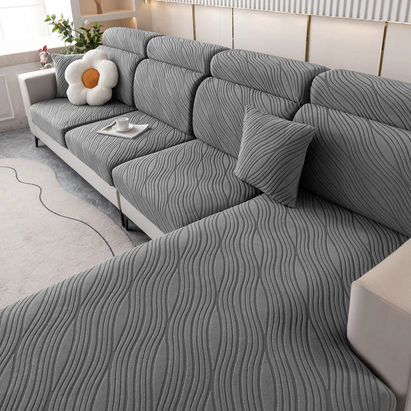 A gray plush elastic sofa cushion cover featuring a fine, wavy texture and a white decorative pillow.