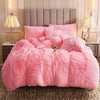 A fluffy pink plush duvet cover set displayed on a bed with a padded headboard and bedside tables.