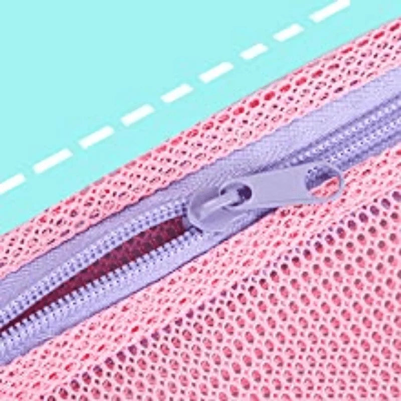 Close-up of a pink mesh beach bag with a purple zipper and silver hardware.