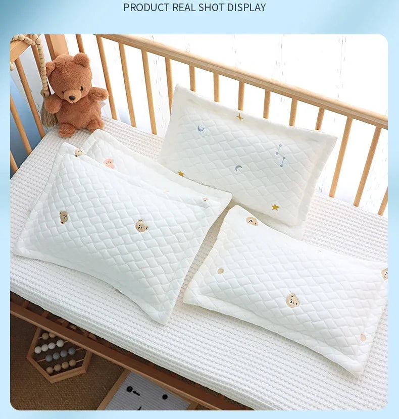 A display of soft white quilted pillows for newborns and babies on a wooden crib railing.