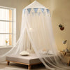 White sheer mosquito net canopy draped over a bed, featuring light blue triangular accents.