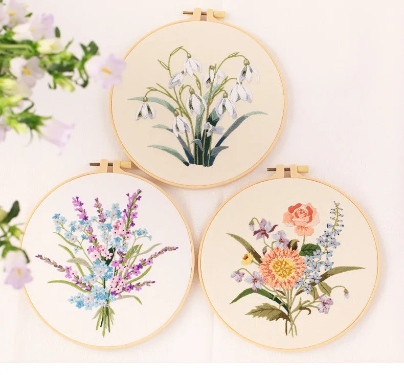 Three circular embroidery hoops displaying floral patterns on light fabric.