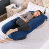 A woman is relaxing on a blue U-shaped maternity body pillow on a white bed.