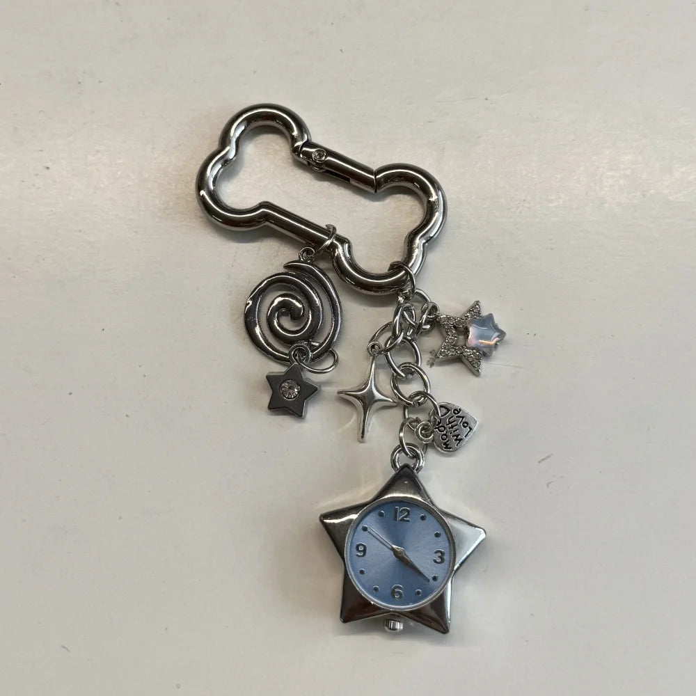 Silver keychain featuring a star-shaped pocket watch with a blue face and decorative charms.