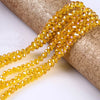A close-up of yellow faceted rondelle glass beads strung together, resting on a cylindrical object.