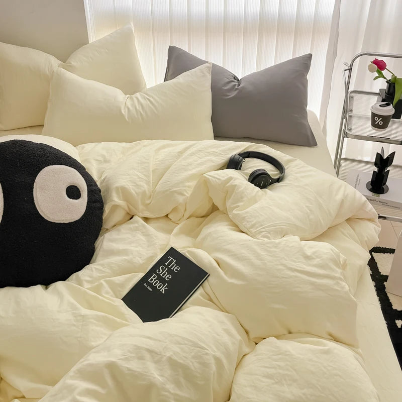 A white duvet cover set with pillows and a black stuffed animal resting on the bedding.