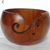 A wooden yarn bowl with a curved lip designed for crochet and knitting organization.