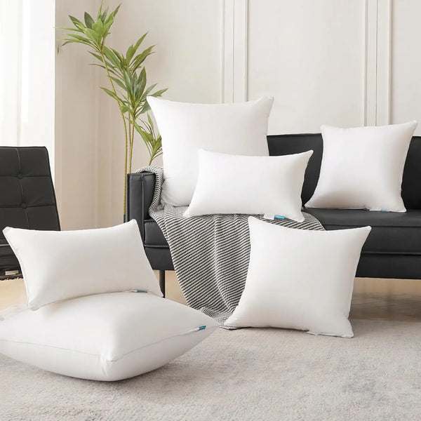 A collection of white and black square cushions displayed on a dark sofa with a striped throw blanket.