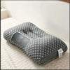A gray ergonomic contour neck pillow with a honeycomb pattern resting on a light-colored textured surface.