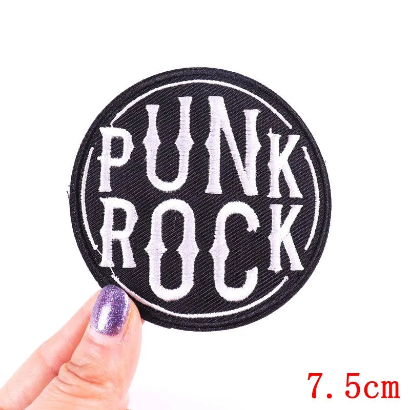 Black embroidery patch with white text PUNK ROCK on a finger