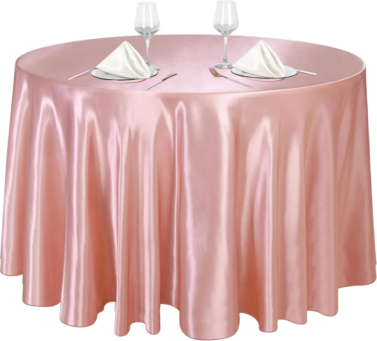 A round table set with a pink satin tablecloth, two wine glasses, and silverware for elegant decor.