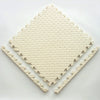 A beige soft interlocking foam play mat with a diamond pattern is shown on a white surface.