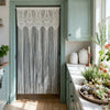 Vintage lace tassel door curtains in gray hanging on a light green door frame.