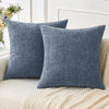 A solid blue gray chenille throw pillow cover resting on a light beige knitted blanket.