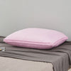 A pink luxury goose down and feather bed pillow resting on a gray blanket.