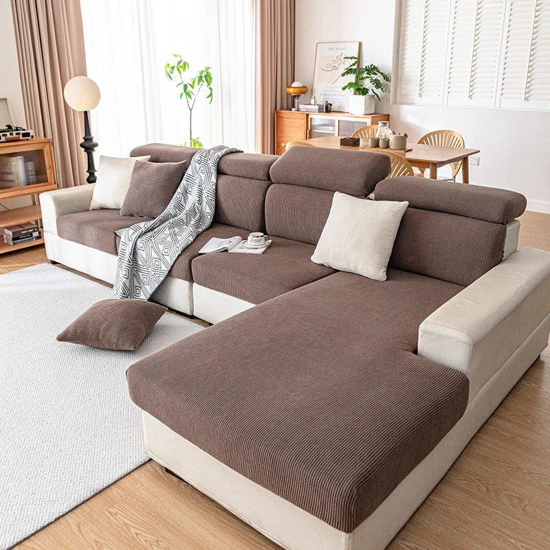 A modern, sectional sofa upholstered in brown fabric with cream accents and a gray patterned throw blanket.