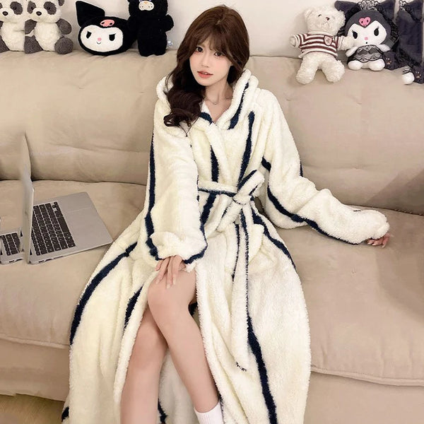 A woman wearing a white and navy striped fluffy kimono robe indoors with plush toys in the background.