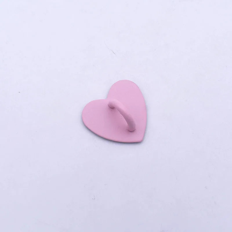 A small, pink metal heart charm connector for phone cases.