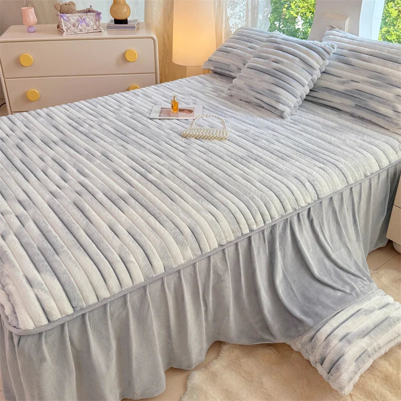 A plush light blue linen bed skirt with vertical pleats covers a bed, next to a wooden dresser.