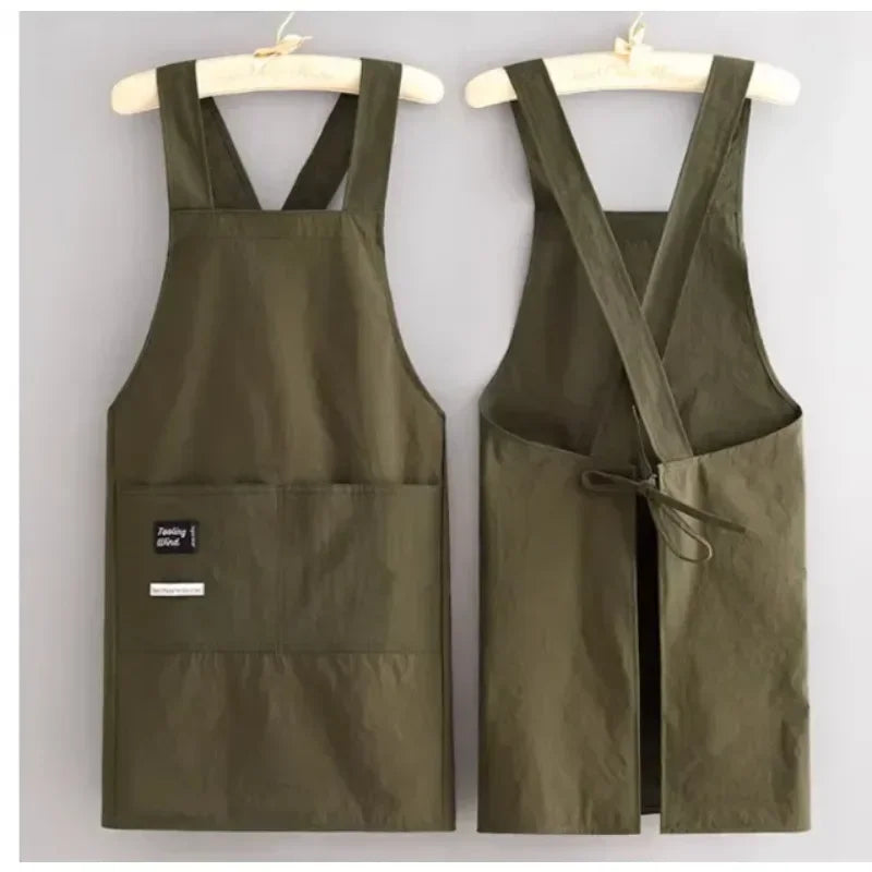 A dark olive green water-resistant kitchen apron with adjustable straps hanging on a wooden hanger.
