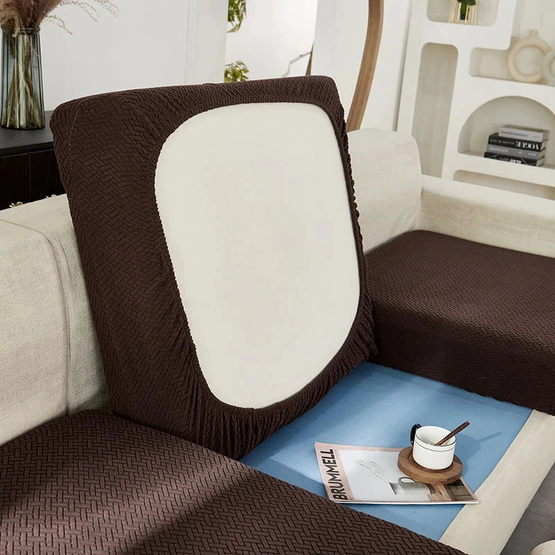 A dark brown jacquard sofa slipcover with white cushions and blue accents on a light-colored couch.