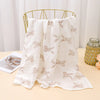 White printable cotton crib sheets with a subtle fawn pattern draped over a gold metal hanger.