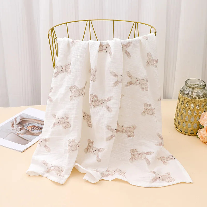 White printable cotton crib sheets with a subtle fawn pattern draped over a gold metal hanger.