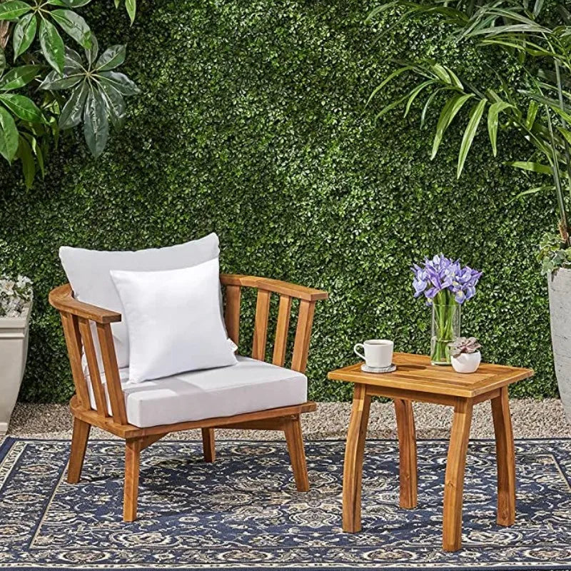 A wooden chair with a white cushion is placed in front of a green moss wall and a small wooden table.