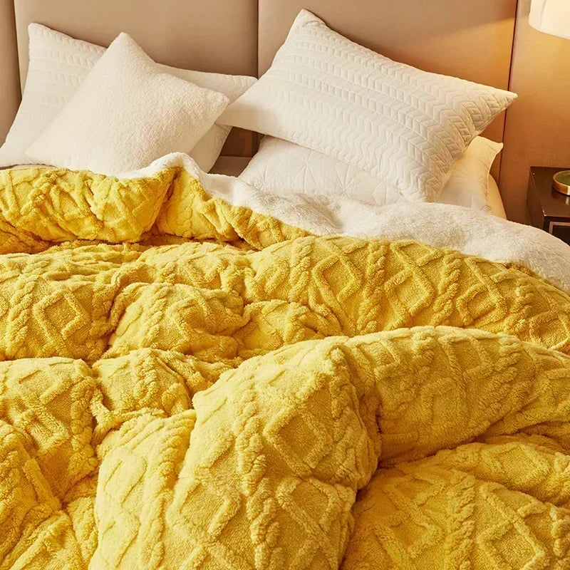 A bright yellow cozy fleece blanket is folded on a bed with white pillows.