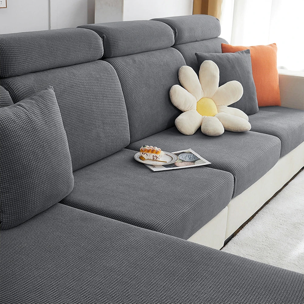 A gray polar fleece jacquard sofa seat cushion cover with an orange flower accent on a modern sofa.