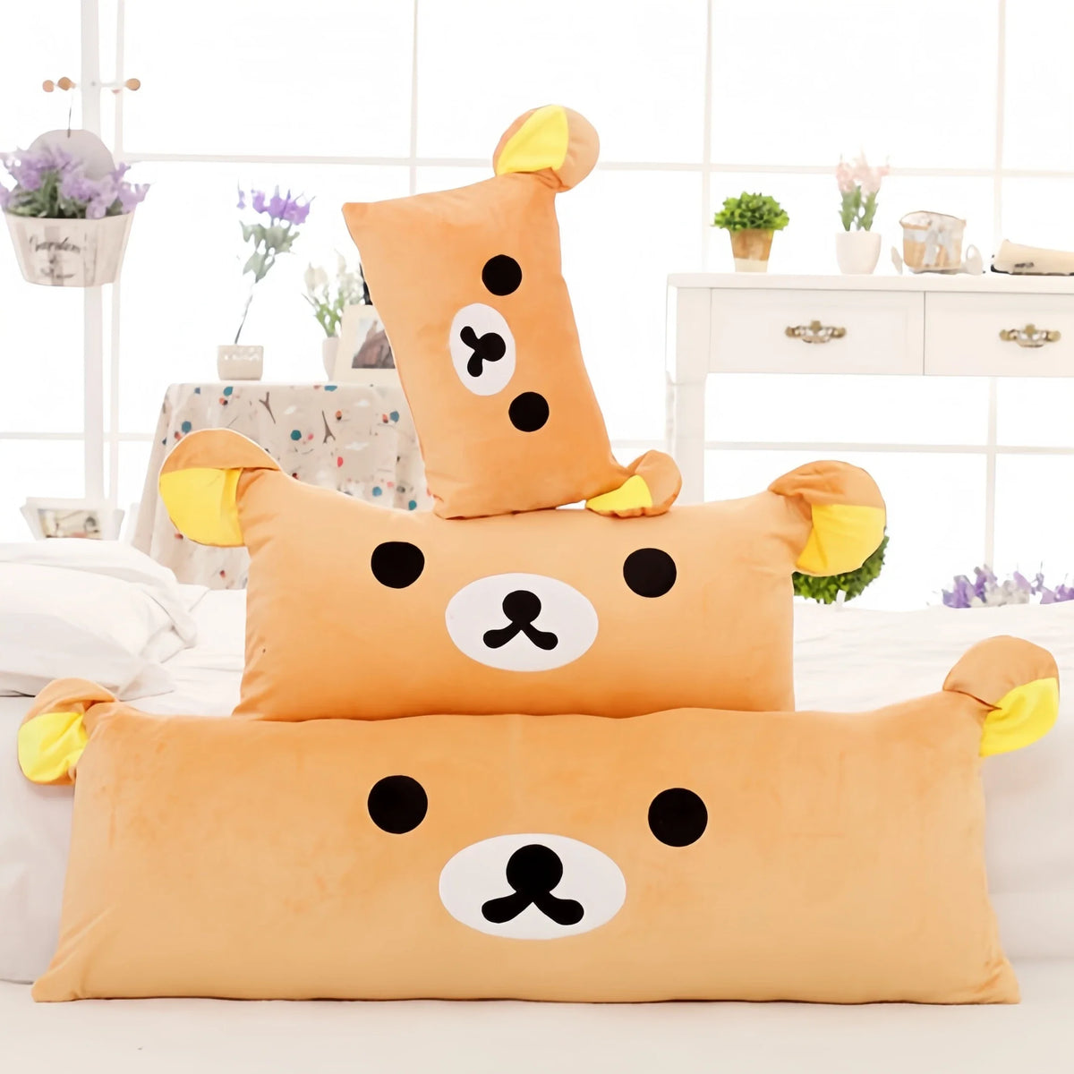 An orange Rilakkuma plush bed pillow and sofa cushion with black facial features resting on a white surface.