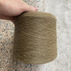 A hand is holding a large spool of natural beige hand-woven wool and linen blended yarn.