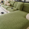 A moss green patterned jacquard sofa cover featuring a branch design on a modern sectional sofa.