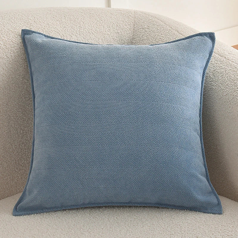 A light blue chenille throw pillow cover resting on a beige sofa.
