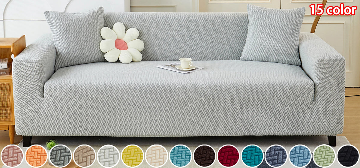 A light gray jacquard elastic sofa slipcover displayed on a sofa with matching pillows and decorative fabric swatches.