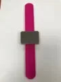 A pink magnetic wrist pincushion with a black rectangular insert and silicone band.