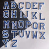 A collection of blue alphabet embroidery iron-on patches arranged in a grid.
