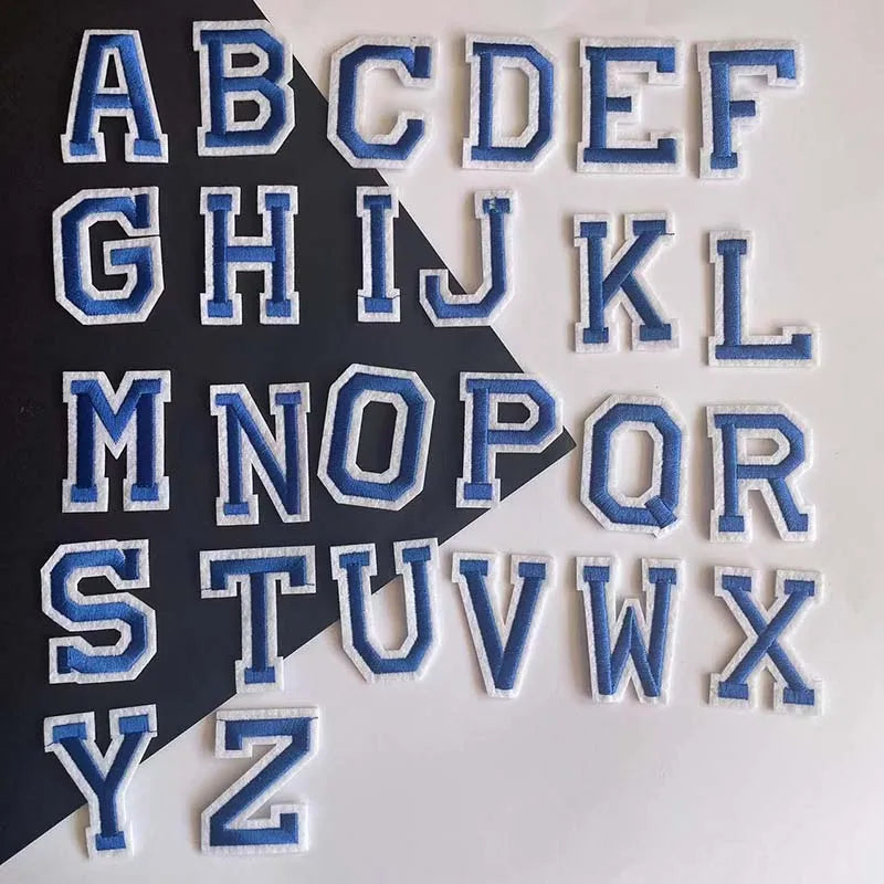 A collection of blue alphabet embroidery iron-on patches arranged in a grid.