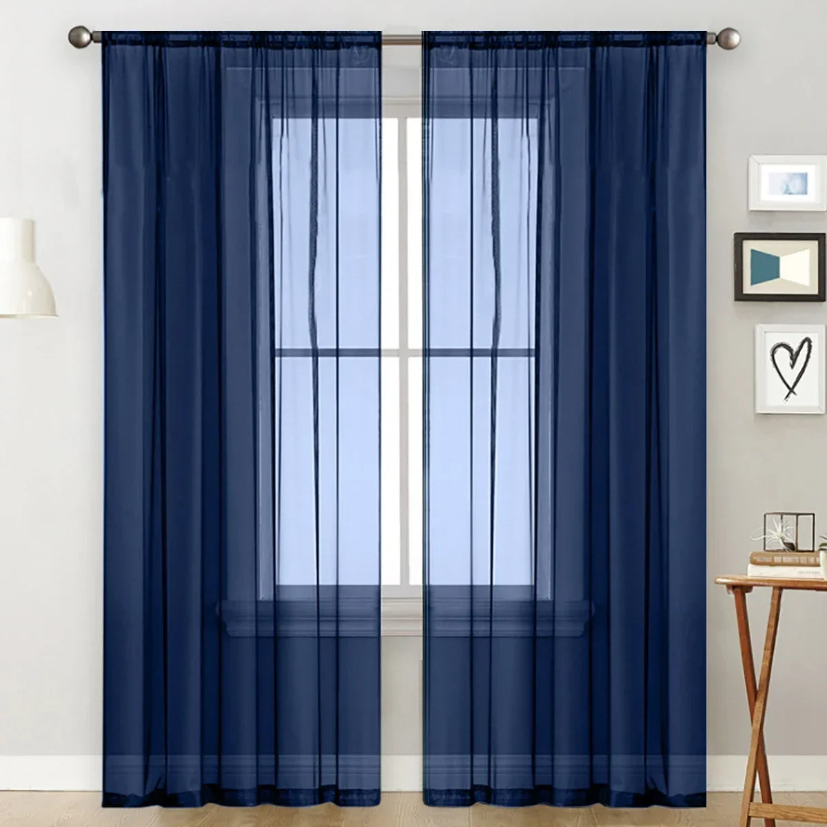 Navy blue sheer curtain with a rod pocket hanging over a white window frame.